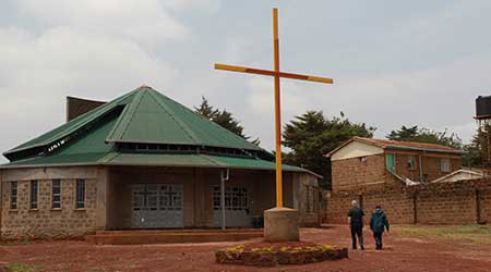 priest and a man walking by a church in Africa